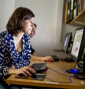 A woman works on a computer in an office.