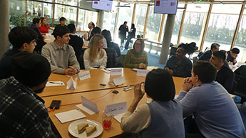 Sarah King sat at a table talking to students at the Beyond the Classroom event. Other tables with students talking to an industry expert are visible in the background.