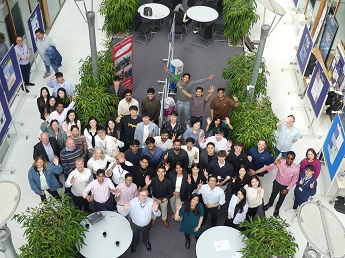 Large group of students and staff from the Entrepreneurship Consultancy project 2025 looking up and smiling