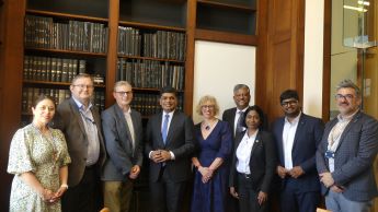 Group image of academic representatives from Kumaraguru Institutions and Nottingham University Business School in the executive suite at University Park campus standing in front of class cabuets with books inside: Sara Turner, Andrew Bacon, Nigel Mongan, 