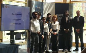 MSc Company Consultancy Competition presentation. Team for Busch Vacuums, runners up standing in front of a large banner: Mentor David Pemberton, Business partner Garvit Mehta, students Mohan Ashok Gowda, Nishita Rattesar, Ruwaid Wange, Saili Sawantt, Yu 