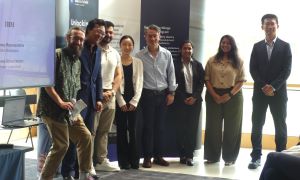 MSc Company Consultancy Competition presentation. Team for IBM, runners up standing in front of a large banner: Dan Gill from Business School, Business partner John McNamara, students Akshaya Subramanian, Jin Hongda, Murad Al Nimri, Priyanka Deepak Nale, 