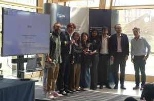 MSc Company Consultancy Competition presentation. Team for IBM, winners standing in front of a large banner holding a silver trophy: Dan Gill from Business School, Business partner John McNamara, students  Clara Benita Jesula Justin Thomas, Kathryn Sugeng