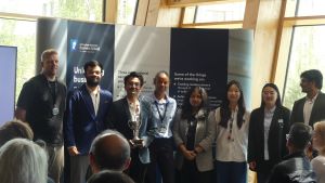 MSc Company Consultancy Competition presentation. Team Notts County Foundation runners up standing in front of a large banner holding a silver trophy: Mentor Professor Andrew Bacon, Business partners Emma Trent and Josh Stevenson, students Aakash Paramesw