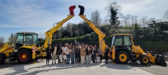 Group of MSc students standing outside under 2 JCB yellow diggers