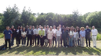 Academics and attendees at the Network of Industrial Economists (NIE) Symposium and Conference 2025, standing in a group standing on grass in front of the lake at Jubilee Campus