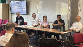 Academics sitting in a row at a roundtable discussion  at the Network of Industrial Economists (NIE) Symposium and Conference 2025