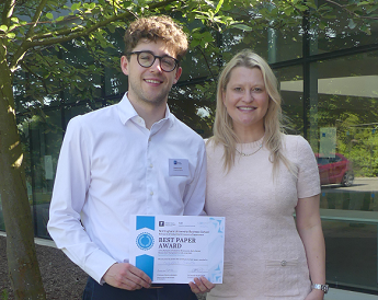 Sponsor Domilė Butkevičiūtė, Principal from Charles River Associates presenting a certificate to the best paper winner Augustus Smith from the University of Oxford at the Network of Industrial Economists (NIE) Symposium and Conference 2025. Both smiling a