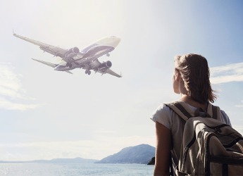 A young woman looking up at plane flying overhead