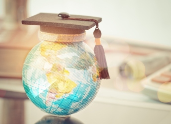 A graduation cap on top of a globe ornament.