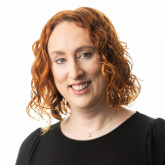 Head and shoulders photo of Claire Mulholland. Claire has red hair and is wearing a dark blouse.