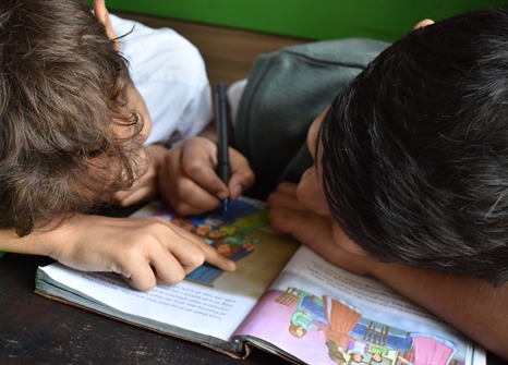 Two children reading and writing in a book
