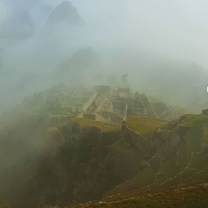 A moody shot on a mountain in Peru looking down through mist at Machu Picchu