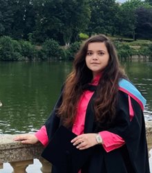 Melania Burlacu, standing in front of Highfileld's Lake in her graduation gown.