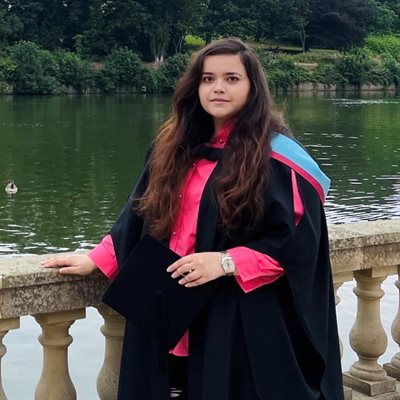 Melania Burlacu dressed in graduation robes in front of lake