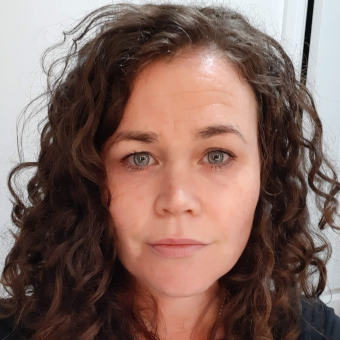 A photo of Olivia Walsh. She has dark brown curly hair and light blue eyes.