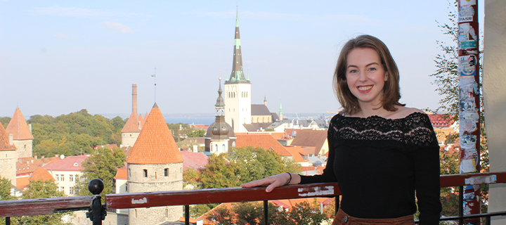 Kathryn wearing a black top and smiling on a balcony overlooking an Estonian mediaeval town.