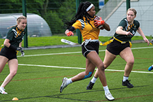 Tamaratare wearing a yellow and black strip whilst playing American Flag Football. She's caught in action mid-game.