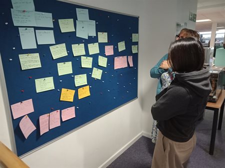 Two attendees pictured reading and reflecting on input shared by fellow attendees in response to the 'What's Your Story' task.