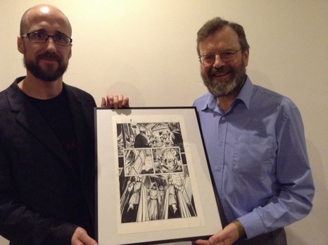 Image of two white men, each standing holding opposite sides of a framed comic book panel and standing at the camera