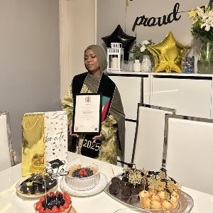 Aya Targoni showing her degree certificate infront of a table of food