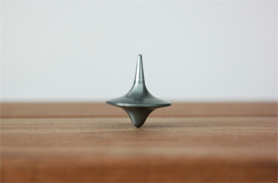 Photo of silver coloured spinning top on a wooden floor