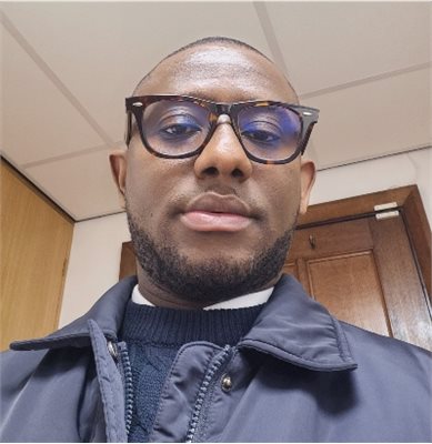 Photo of Godfred Kwarteng wearing glasses and smiling at camera