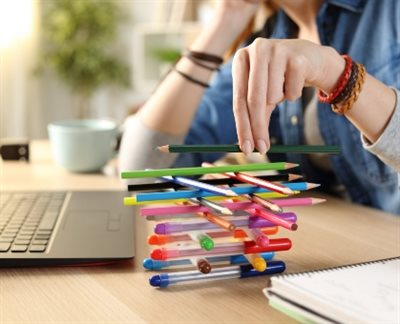A person playing a game of building pens into a block while sat at their laptop