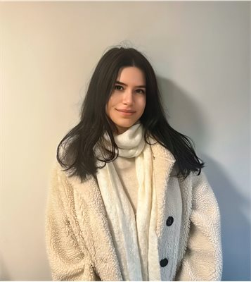 Photo of politics student Yana Angelova wearing a white fur coat in front of a plain white wall