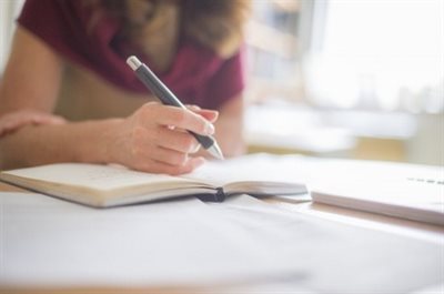 A woman is writing in a notebook.