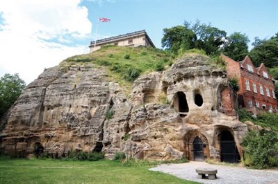 Sandstone cliff and gated cave entrance of Mortimer&amp;#39;s Hole and Castle Rock