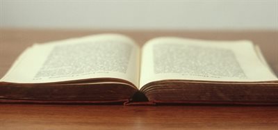 Photo of a large manuscript lying open on a wooden table