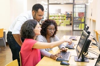 Three people of different ethnicities at work looking at a computer