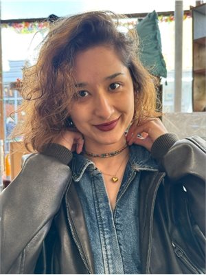 Photo of Subinuer Kuximake wearing a black jacket and smiling at the camera