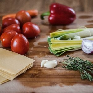 Chopping board with tomatoes, celery, garlic, herbs and leeks