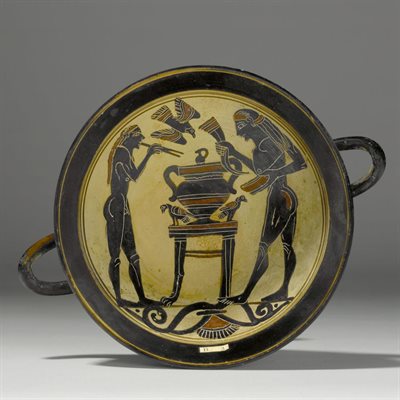 Shallow dish depicting two figures in relief, standing either side of a large cup or urn surrounded by birds. Details in black against a cream background.