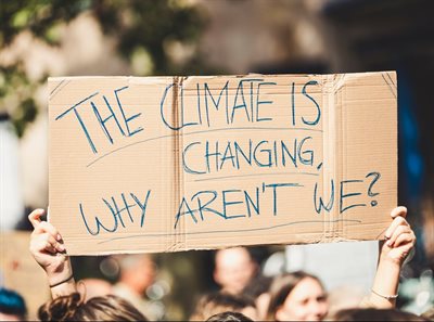 Hands holding cardboard placard saying &amp;#39;The climate is changing, why aren&amp;#39;t we?&amp;#39; Global climate change protest demonstration strike - No Planet B - 09-20-2019