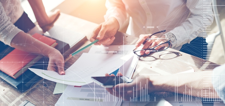 Three people in an office looking at a piece of paper and a calculator