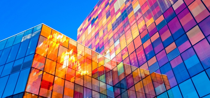 Two high rise office blocks bathed in sunshine so are multicoloured with the light reflecting on the glass