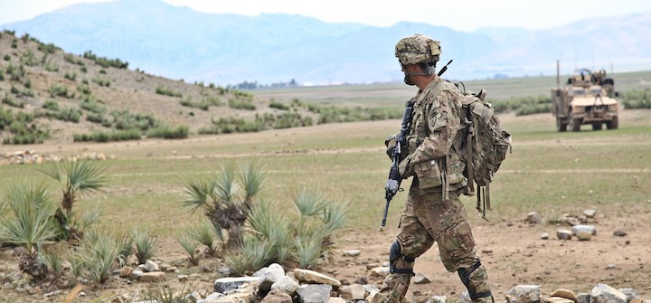 Soldier walking across a desert landscape