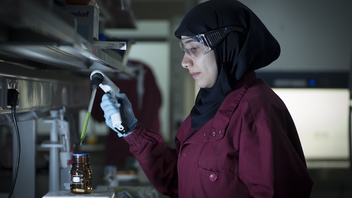 Female scientist uses a pipette to transfer chemicals in a lab