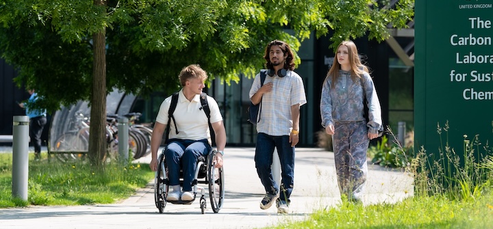 Three students travelling across campus, one student is in a wheelchair