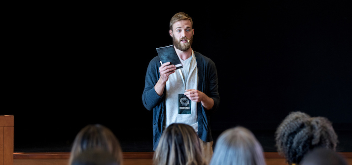 man standing in front of a room of students presenting