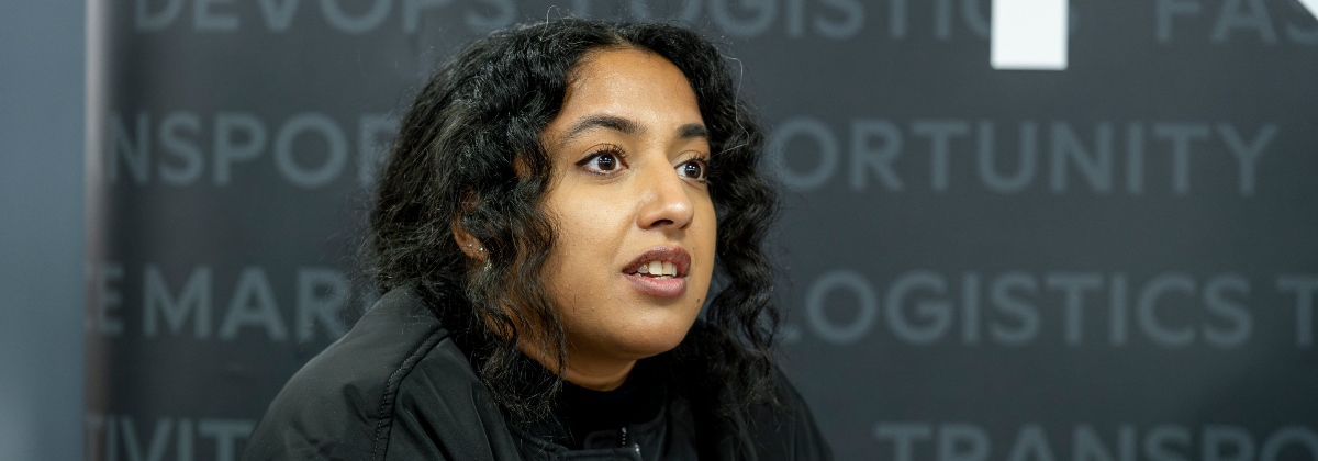A graduate in front of a banner stand with job titles listed on it