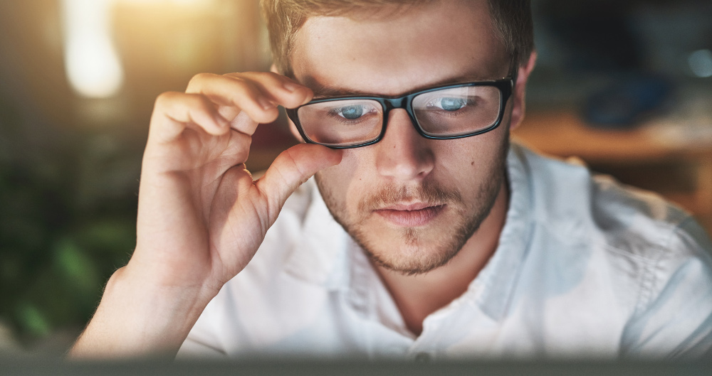 Man in glasses looking at a computer screen
