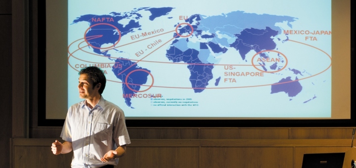 Lecturer in front of screen showing a world map