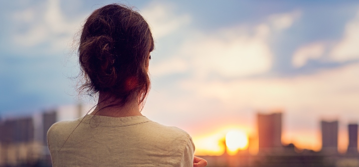 Woman looking over a city skyline in the late evening