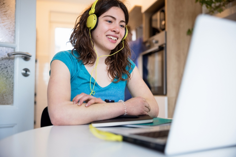 Young woman with headphones looking at a laptop screen