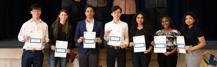 Group of scholarship winners standing in a line holding certificates