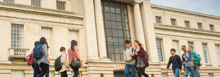 Undergraduate students walking and relaxing outside Portland building 714x249